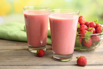 Glasses of milkshake with strawberries on table close up