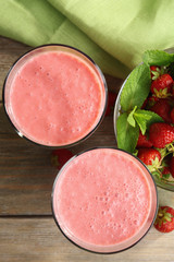 Glasses of milkshake with strawberries on table close up
