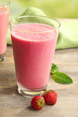 Glasses of milkshake with strawberries on table close up