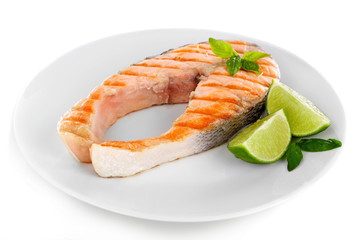 Tasty grilled salmon with lime on plate close up