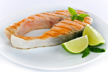 Tasty grilled salmon with lime on plate close up