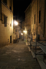 Fototapeta na wymiar Dark narrow alley with old buildings and street lamps in Siena,Tuscany, Italy