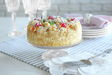 Butter cake with cherries on stand and table setting, on light background