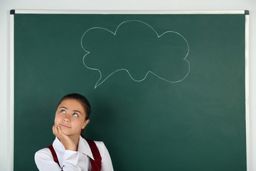 Beautiful little girl standing near blackboard