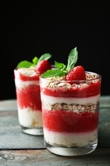 Dessert with fresh strawberry, cream and granola, on wooden table, on dark background