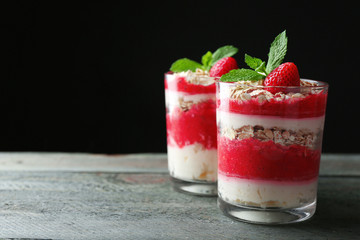 Dessert with fresh strawberry, cream and granola, on wooden table, on dark background