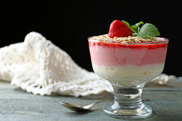 Dessert with fresh strawberry, cream and granola, on wooden table, on dark background