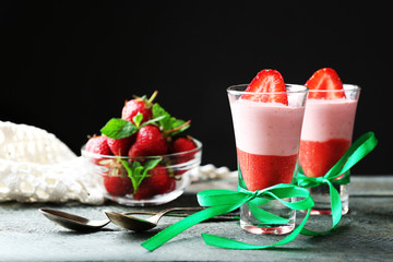 Fresh strawberry yogurt dessert in glass, on table, on dark background