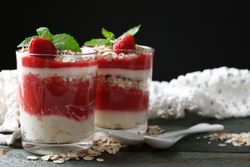 Dessert with fresh strawberry, cream and granola, on wooden table, on dark background