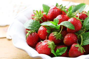 Red ripe strawberries in bowl, on color wooden background