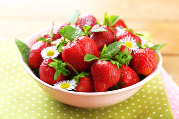 Red ripe strawberries in bowl, on color wooden background