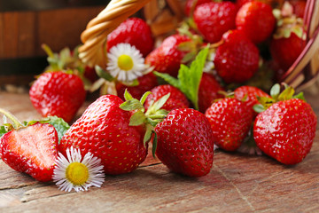 Red ripe strawberries in wicker basket, on wooden background
