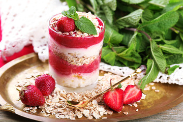 Dessert with fresh strawberry, cream and granola, on tray, on color wooden table background