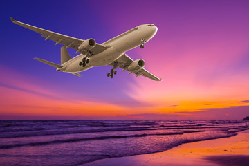 Commercial airplane flying above the sea at sunset