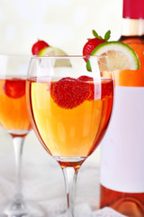Glasses of wine with strawberries and slice of lime on light background