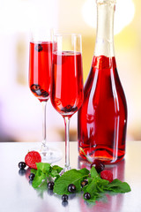 Glass of champagne with berries on light blurred background