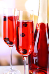 Glass of champagne with berries on light blurred background