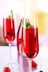 Glass of champagne with berries on light blurred background