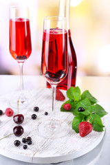 Glass of champagne with berries on light blurred background