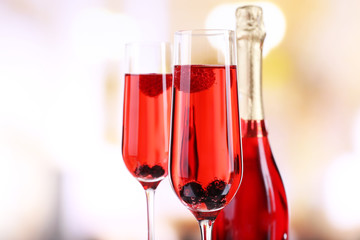 Glass of champagne with berries on light blurred background