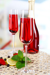 Glass of champagne with berries on light blurred background