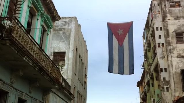 Rustic Cuban flag hanging between the dilapidated colonial architecture on a street in central Havana, Cuba