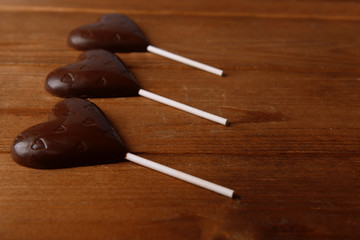 Chocolate candies in shape of hearts on wooden background