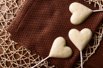 Chocolate heart shaped candies on sticks on brown napkin, closeup