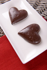 Chocolate heart shaped candies on sticks in white plate, closeup