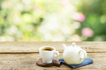 Tea cup with old teapot on wooden table