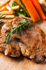 grilled pork chop with vegetable and french fries on wooden boar