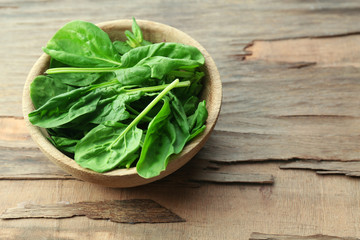 Bowl of fresh spinach leaves on wooden background