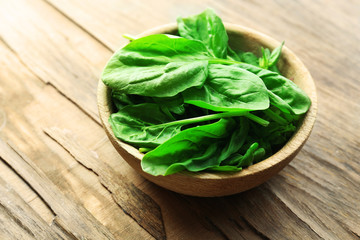 Bowl of fresh spinach leaves on wooden background