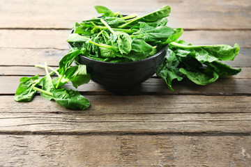 Bowl of fresh spinach leaves on wooden background