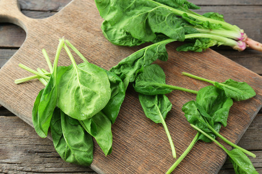 Fresh spinach leaves on wooden cutting board, closeup