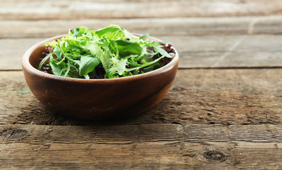 Bowl of mixed green salad on wooden background