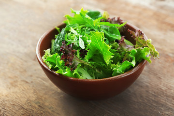 Bowl of mixed green salad on wooden background