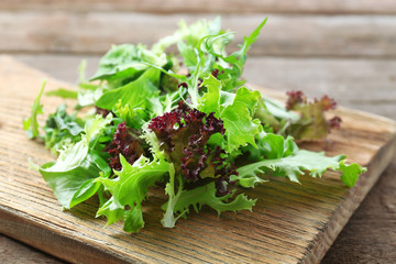 Mixed green salad on wooden cutting board, closeup