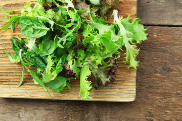 Mixed green salad on wooden cutting board, closeup