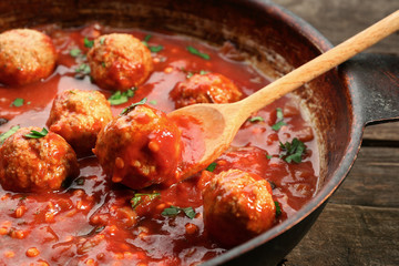 Pan with meat balls in tomato sauce, on wooden background