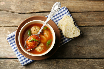 Tomato soup with meat balls on wooden spoon on wooden background