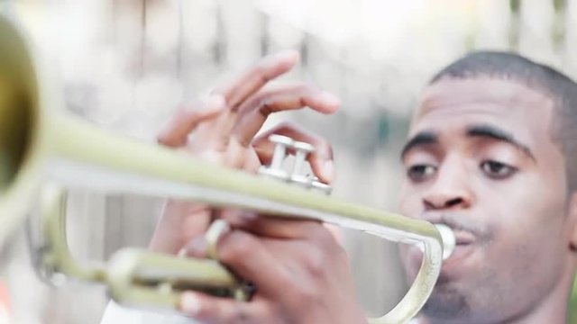 Black man plays a trumpet in the street
