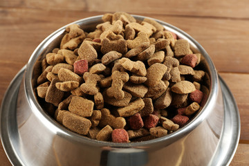 Dog food in bowl on wooden table