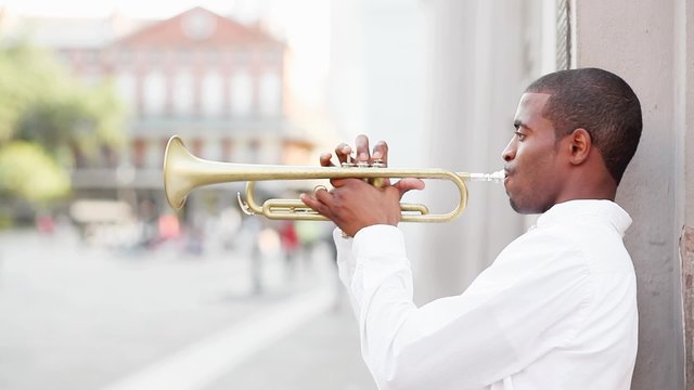 Black man plays a trumpet in the street
