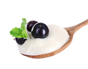 Fototapeta premium Delicious yogurt in spoon with blackcurrants and mint isolated on white