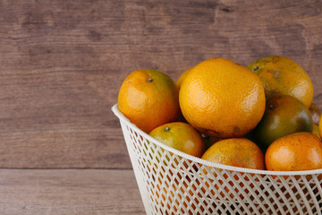 orange fruit in white basket on wood table background
