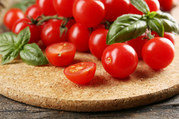 Cherry tomatoes with basil on wooden table close up
