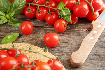 Cherry tomatoes with basil on wooden table close up