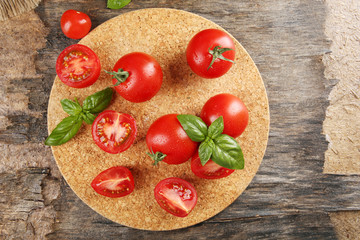 Cherry tomatoes with basil on wooden table close up