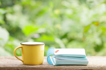 Notebook  and coffee in yellow cup on wooden table